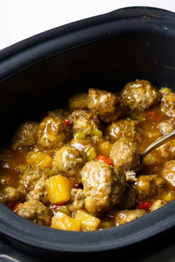 Meatballs in a slow cooker with sweet and sour sauce.