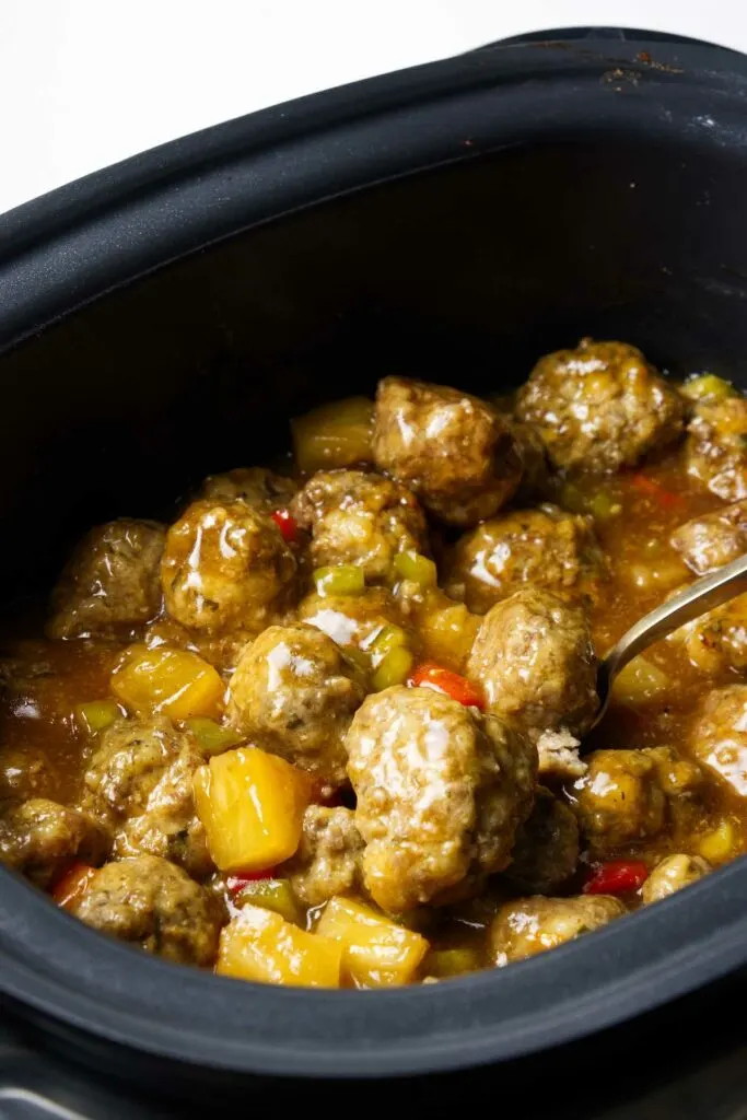 Meatballs in a slow cooker with sweet and sour sauce.