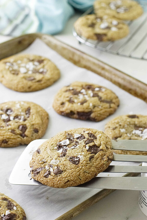 A metal spatula lifting cookies off a baking pan.