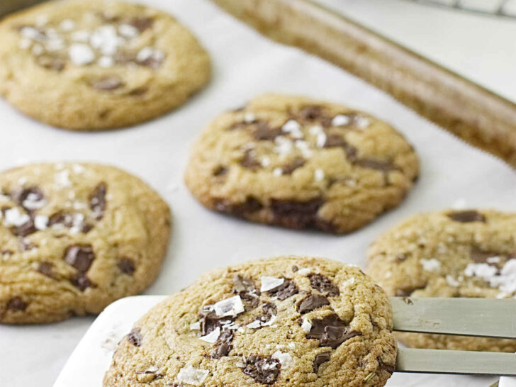 A metal spatula lifting cookies off a baking pan.