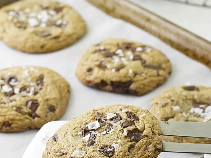 A metal spatula lifting cookies off a baking pan.