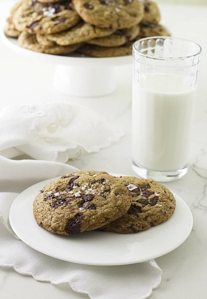 Rosemary chocolate chip cookies made with sprouted flour next to a glass of milk.