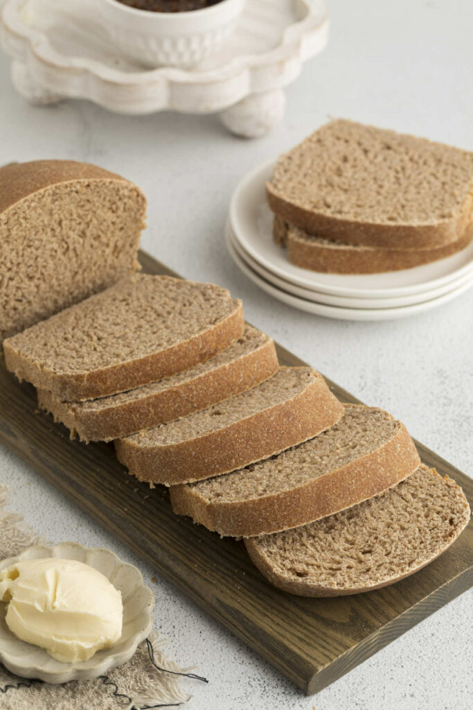 Sliced bread on a cutting board next to butter.