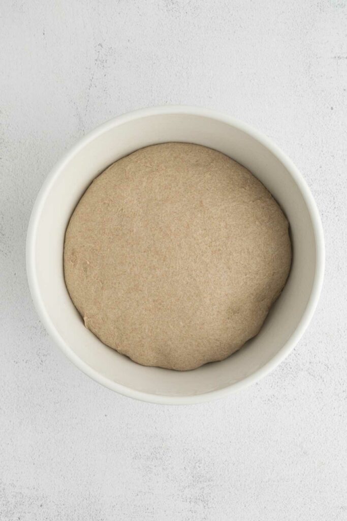 Proofing dough in a white bowl.