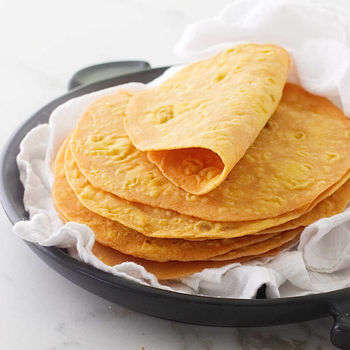 A stack of sweet potato flat bread on a white tea towel.