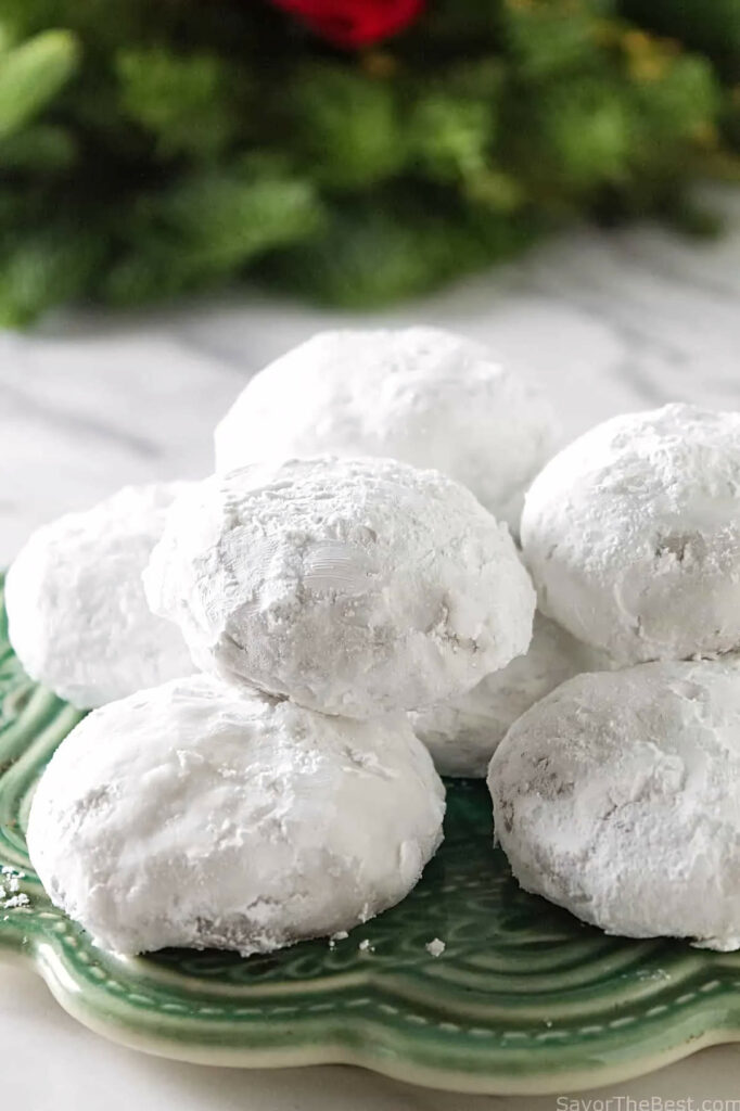 Pfeffernusse cookies on a green plate with a wreath in the background.