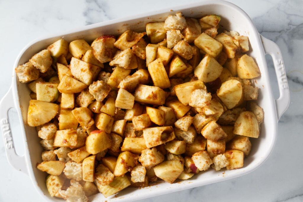 Adding the bread and apple mixture into a baking dish.