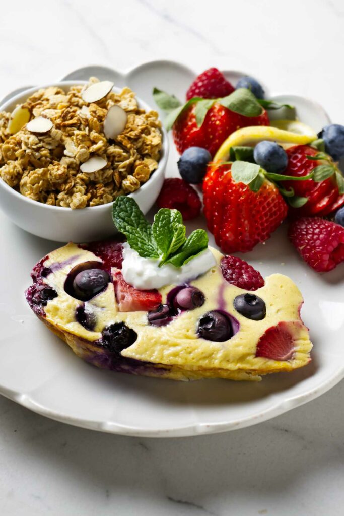 A slice of baked yogurt on a plate with berries and granola.