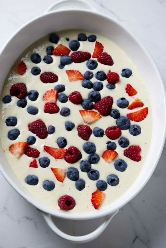 A yogurt custard mixture in a baking dish topped with berries.