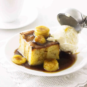 Adding a scoop of vanilla ice cream on top of a slice of banana bread pudding.