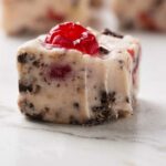 A square of cherry fudge with a bite taken from the corner.