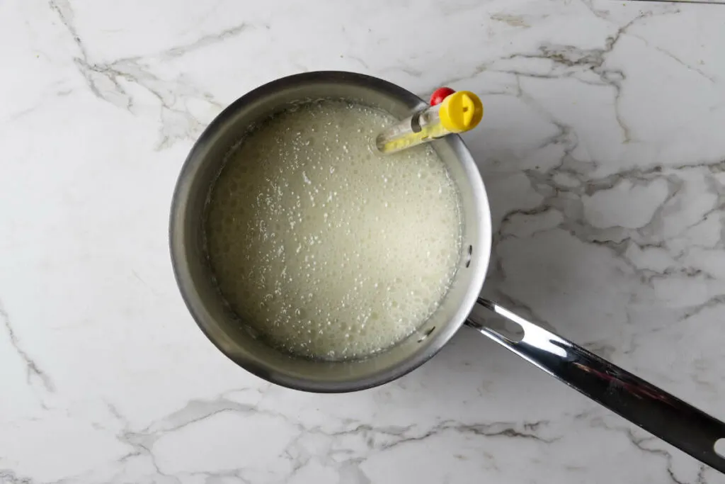 A candy thermometer in a pan of sugar syrup.