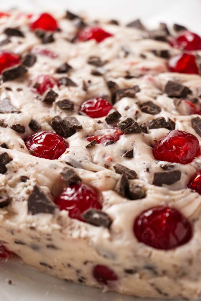 A large block of fudge with cherries and chocolate chunks.