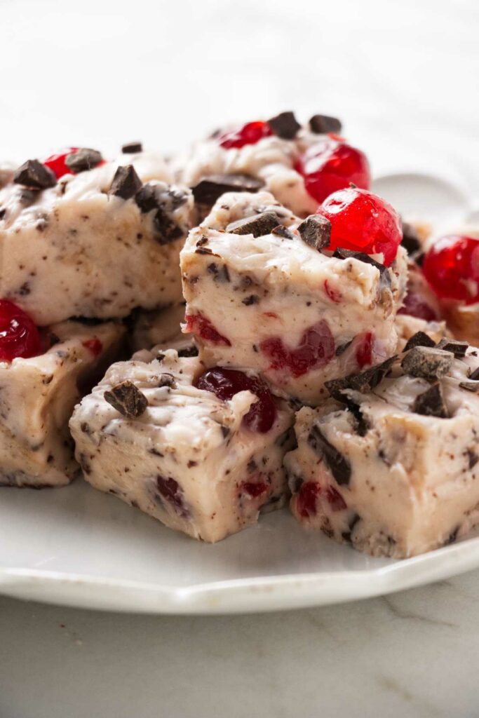 A plate filled with squares of cherry fudge studded with chocolate chunks.