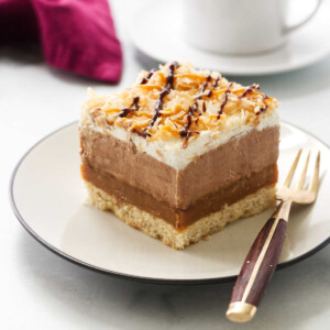 A slice of a chocolate samoa dessert lasagna on a plate with a fork.