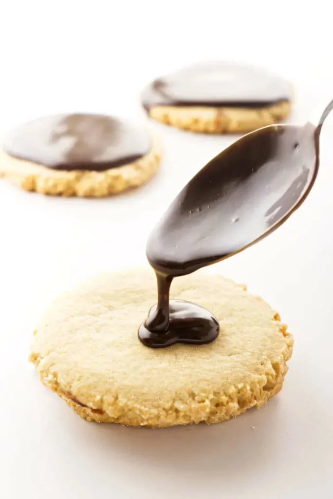 Drizzling chocolate icing over a peanut butter cookie.