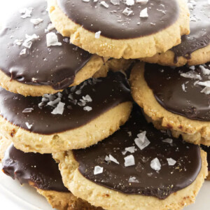 A plate filled with a stack of peanut butter cookies topped with chocolate icing.