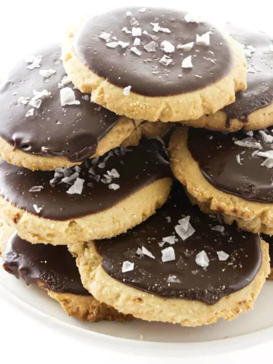 A plate filled with a stack of peanut butter cookies topped with chocolate icing.