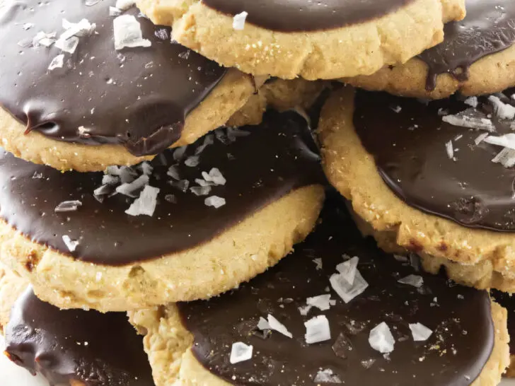 A plate filled with a stack of peanut butter cookies topped with chocolate icing.