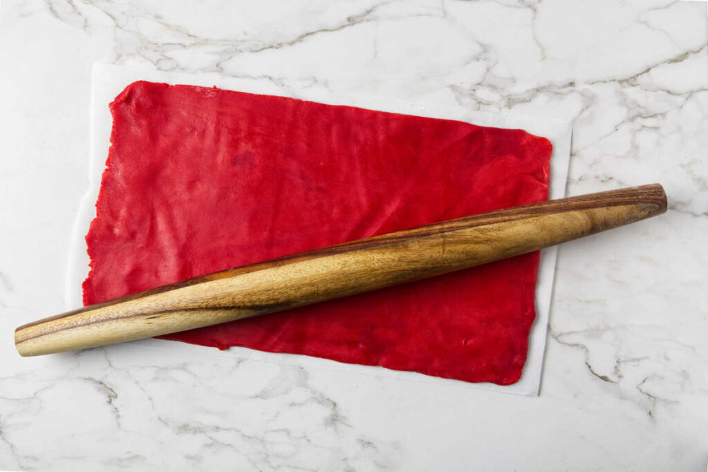 Rolling red cookie dough into a rectangle.