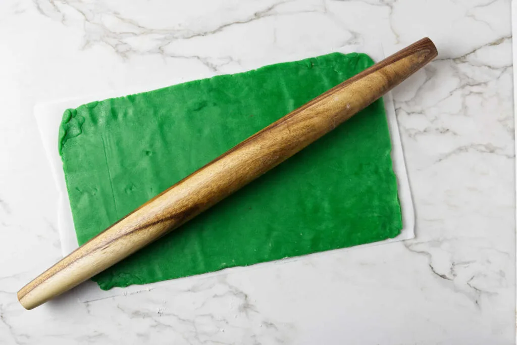 Rolling green cookie dough into a rectangle.