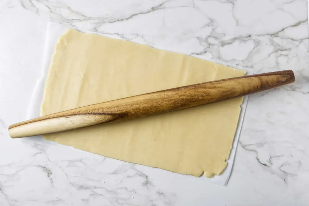 Rolling white cookie dough into a rectangle.