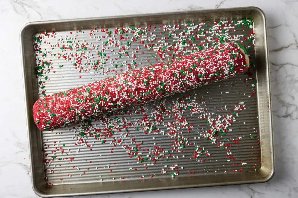 Rolling the log of cookie dough in sprinkles.