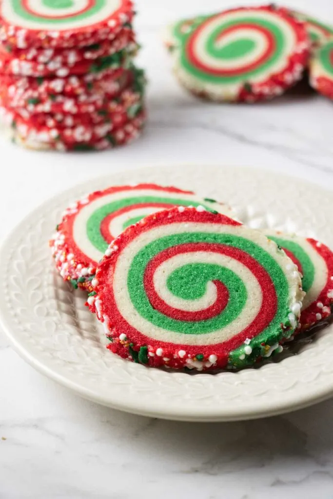 A plate filled with Christmas swirl cookies with red and green layers.