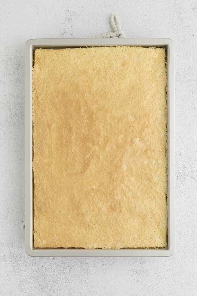 Freshly baked coconut cake cooling in a sheet pan.