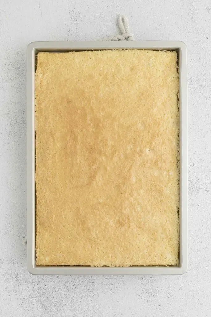 Freshly baked coconut cake cooling in a sheet pan.