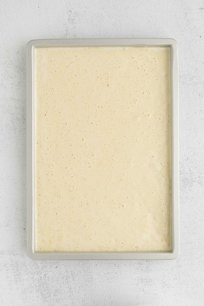 Coconut sponge cake batter on a sheet pan.