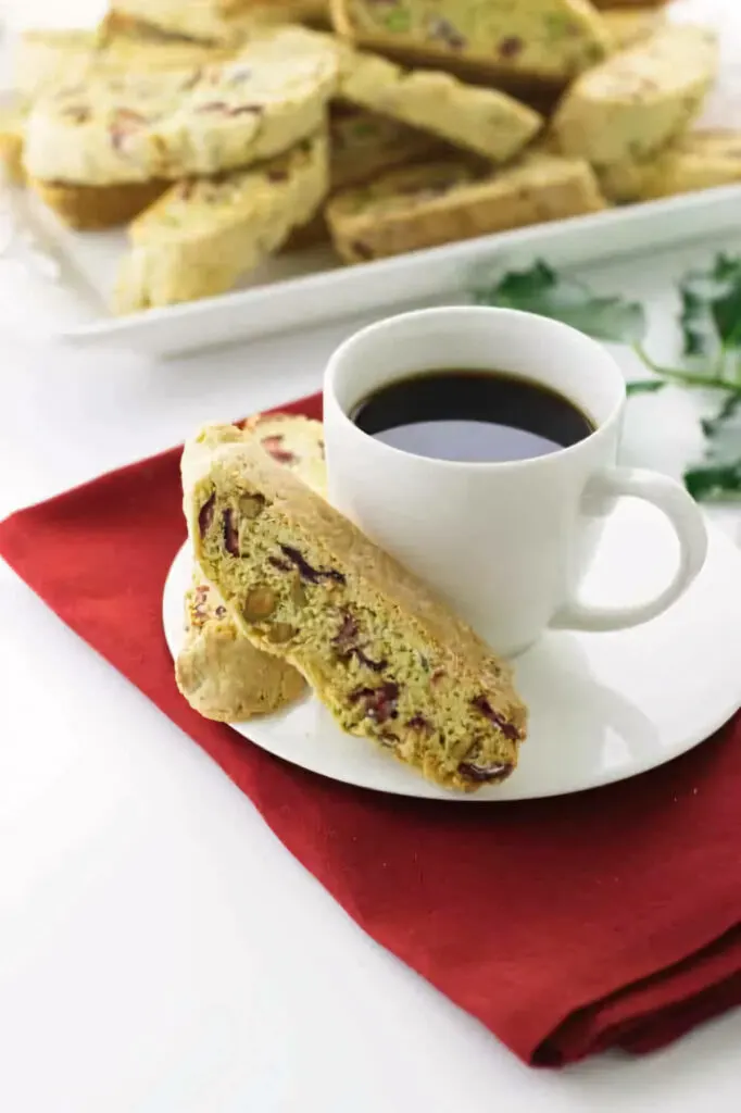 A cup of coffee with several biscotti cookies.