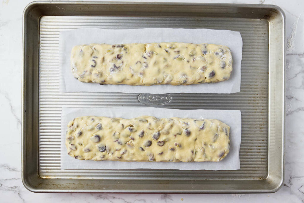 Biscotti dough shaped into logs and placed on a baking sheet ready for the oven.