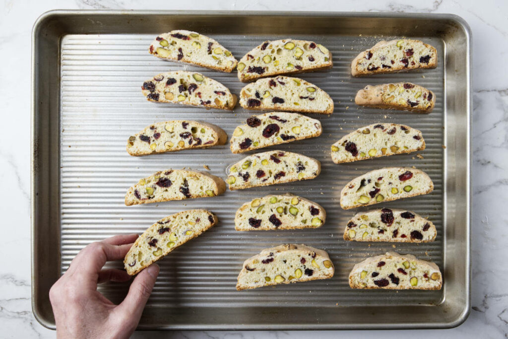 Placing the sliced biscotti on a baking sheet to bake a second time.