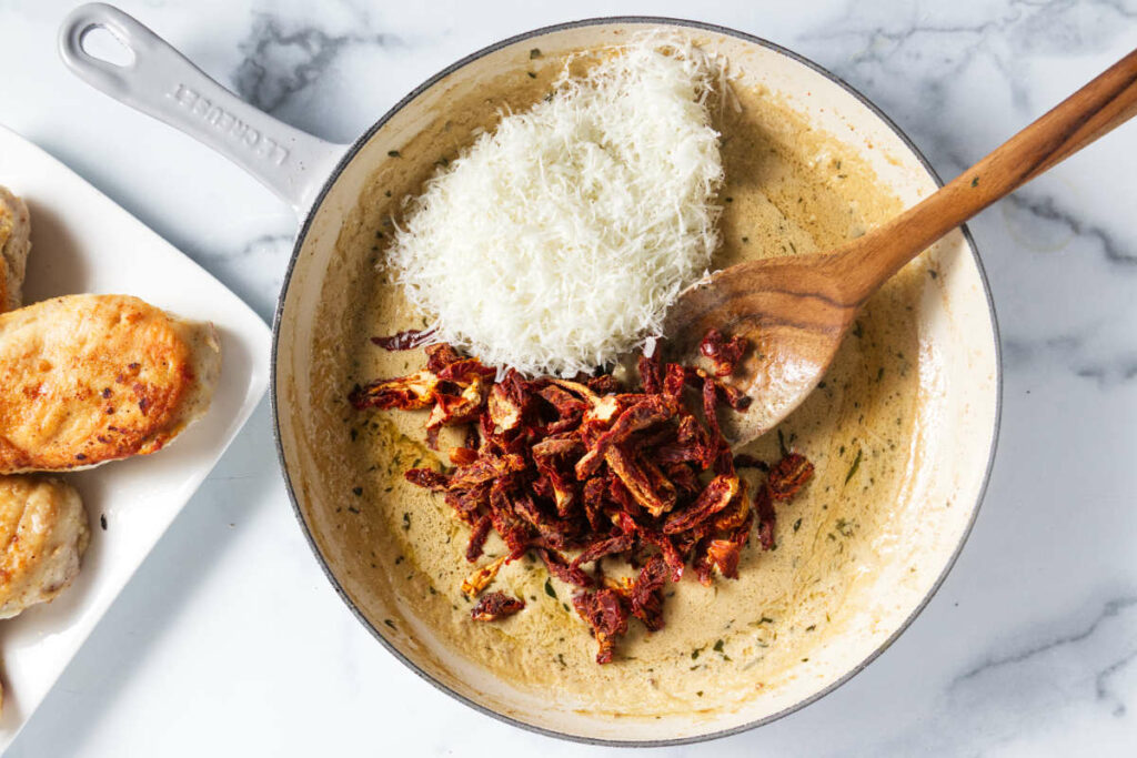 Adding sundried tomatoes and parmesan cheese to the sauce. 