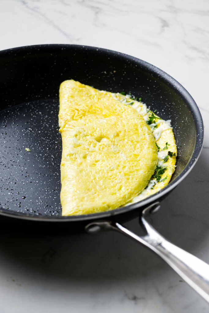 Folding half of an omelet over on itself.