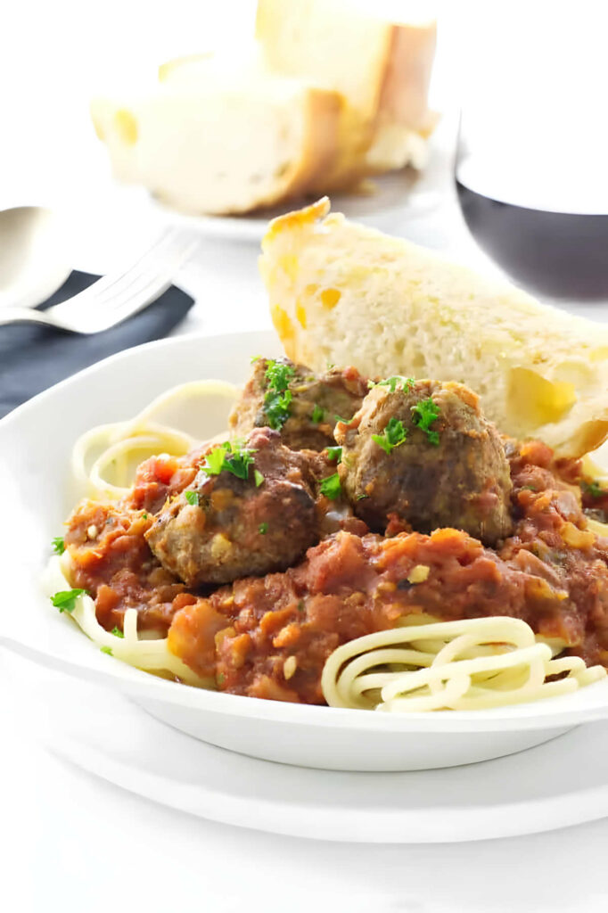 A plate filled with meatballs with Italian sauce and spaghetti.