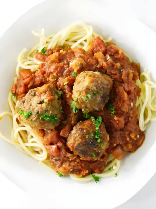 Tomato garlic sauce and meatballs on a pile of spaghetti noodles.