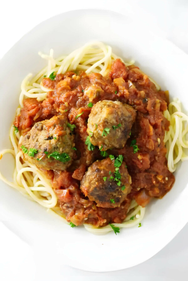 Tomato garlic sauce and meatballs on a pile of spaghetti noodles.