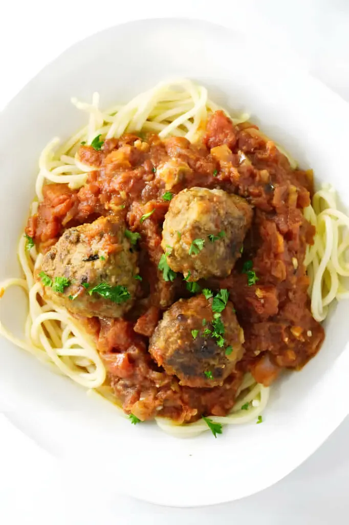 Tomato garlic sauce and meatballs on a pile of spaghetti noodles.