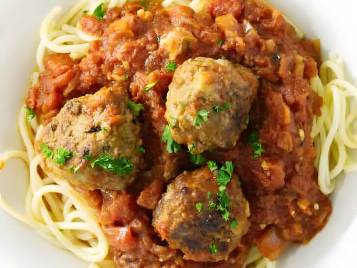 Tomato garlic sauce and meatballs on a pile of spaghetti noodles.