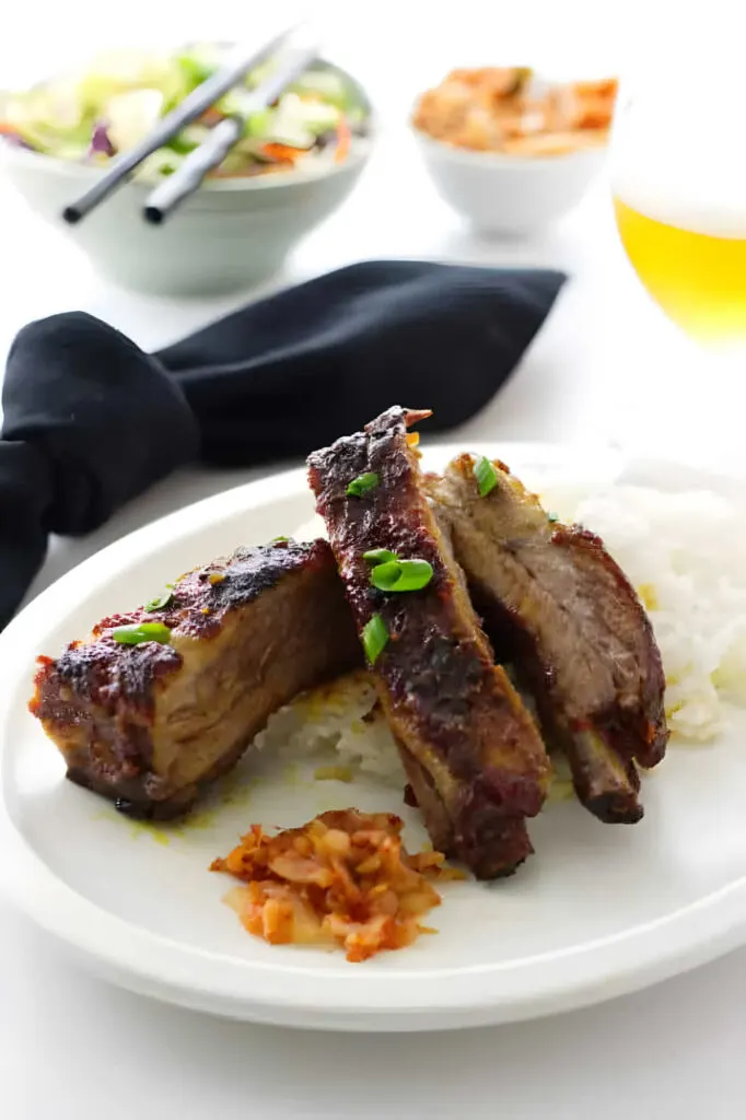 A plate of country style Asian pork ribs with rice and kimchi.