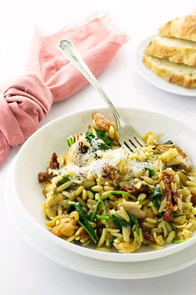 A chicken orzo bowl with kale and parmesan cheese.