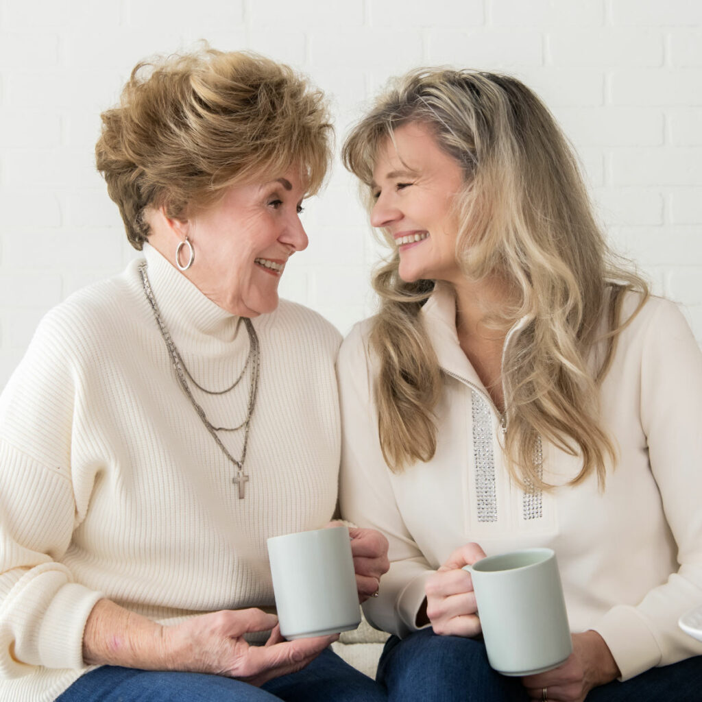 Pat and Dahn sitting on a couch holding cups of coffee.