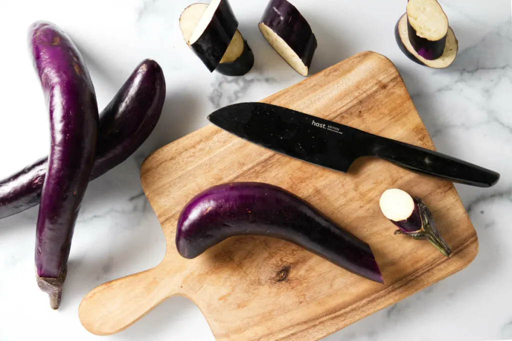 Slicing eggplants on a cutting board.