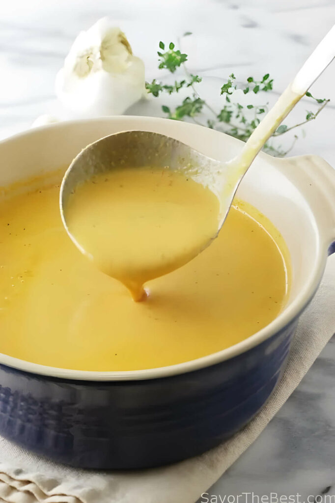 A ladle scooping some roasted tomato soup out of a bowl.