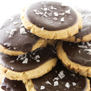 A stack of chocolate coated peanut butter cookies topped with salt flakes.