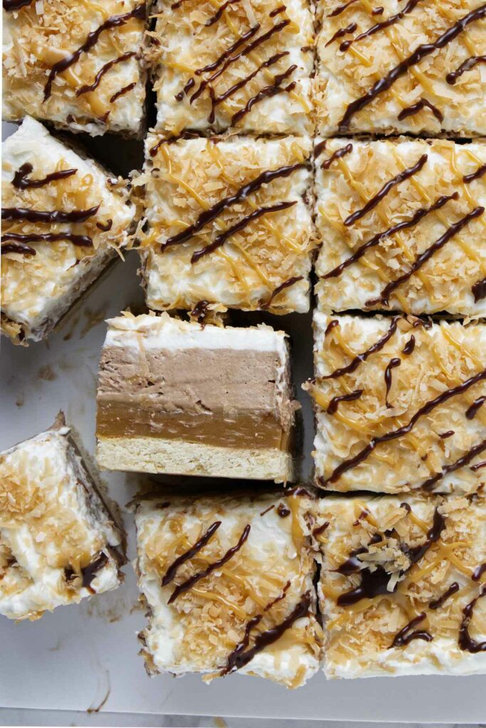 Several slices of a layered no bake cheesecake bar topped with toasted coconut.