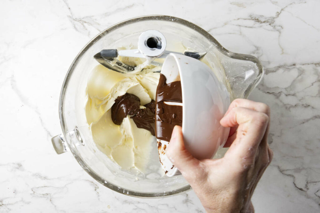 Combining melted chocolate into a cheesecake mixture.