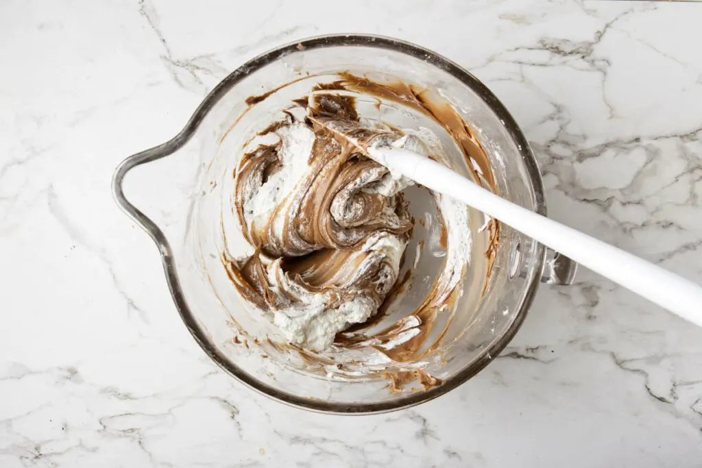 Folding chocolate into a cheesecake mixture.